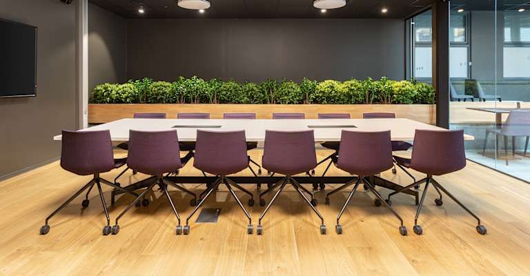 Ett modernt konferensrum i Stockholm med lila stolar och gröna växter.